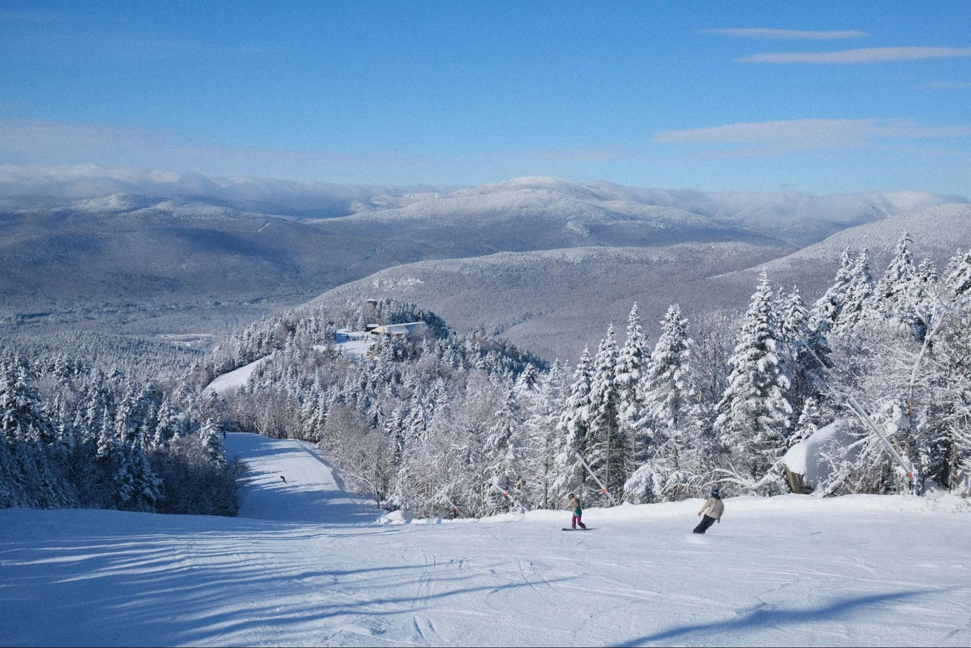 Skiers on a ski slope with mountains in New Hampshire.